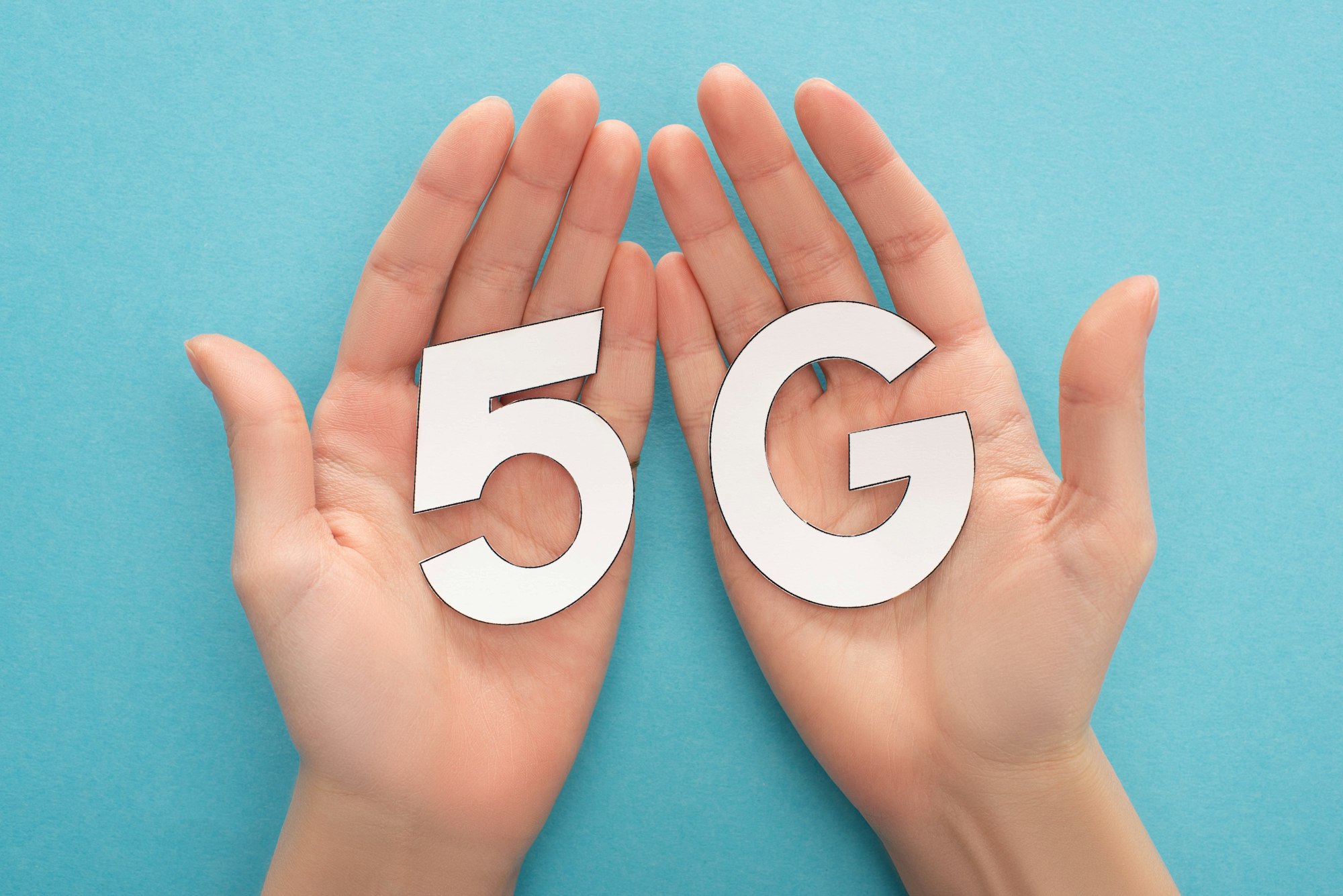 cropped view of woman holding white 5g lettering on blue background