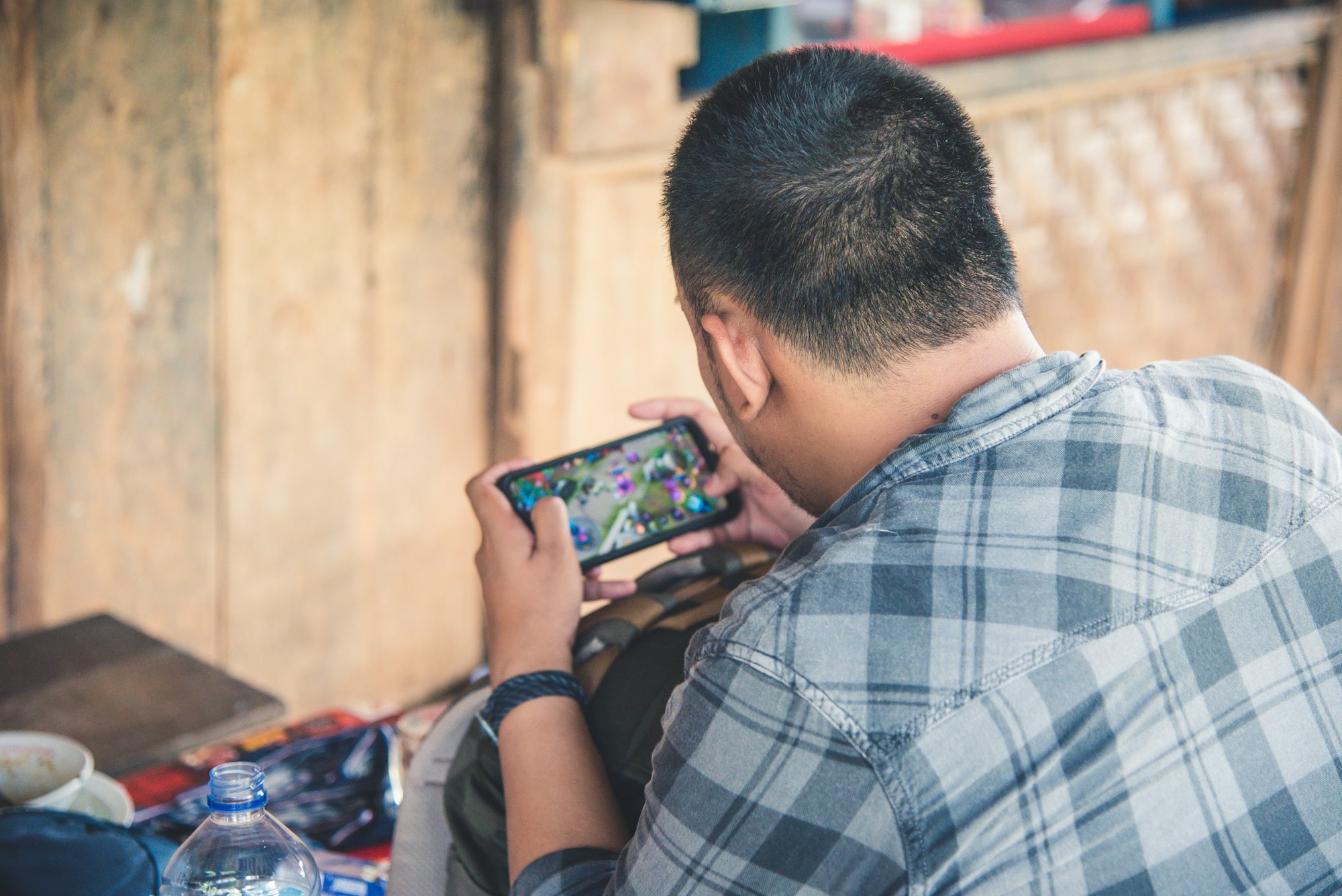 A boy is busy with his cellphone, playing game “Mobile Legends”