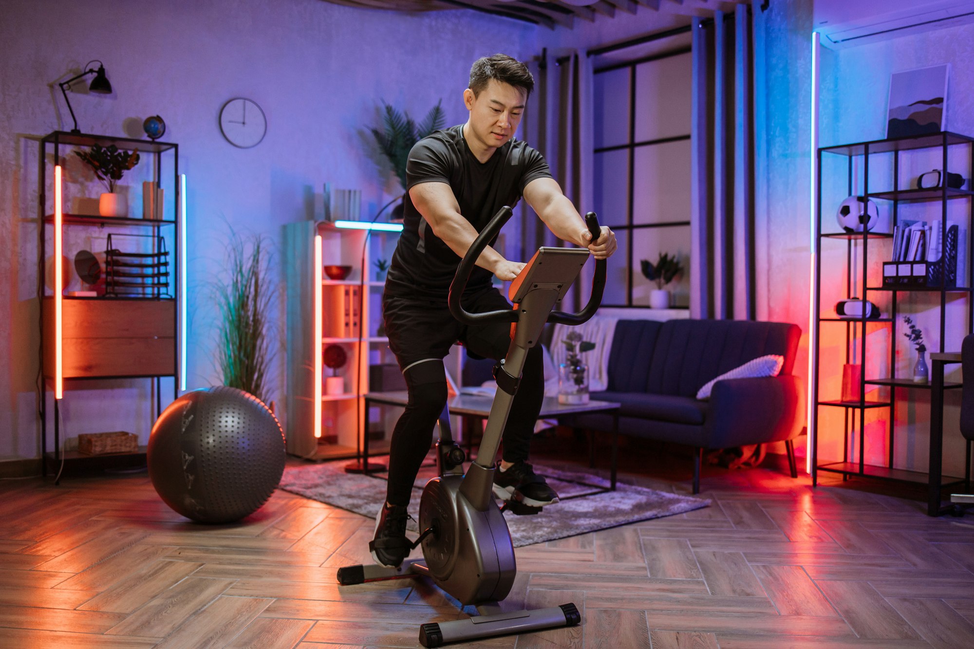 Home fitness workout, young asian man athlete training on smart stationary bike indoors