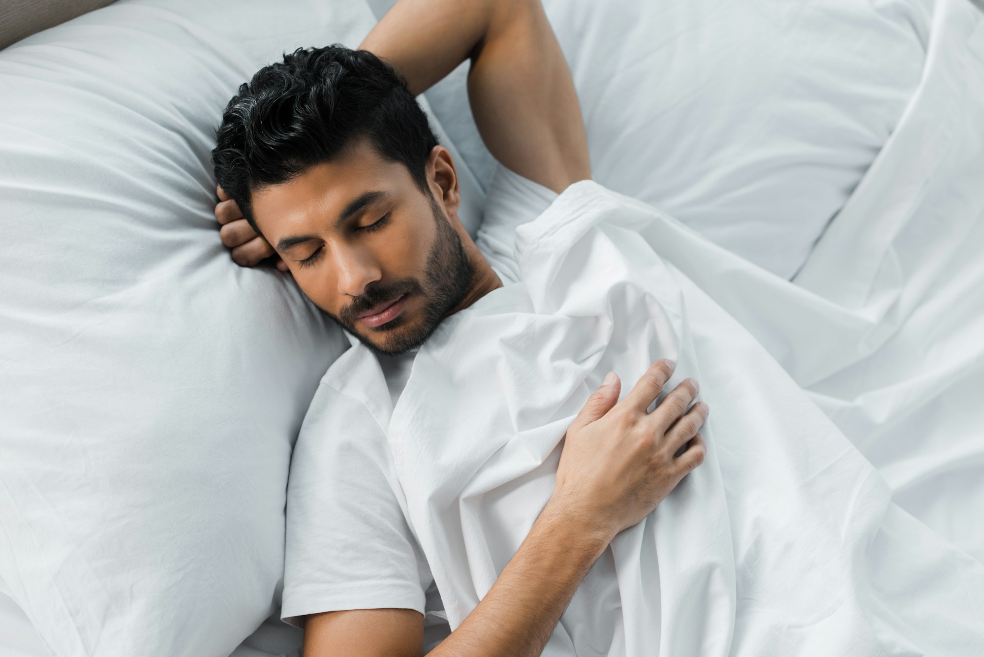 top view of handsome bi-racial man sleeping in bed in morning