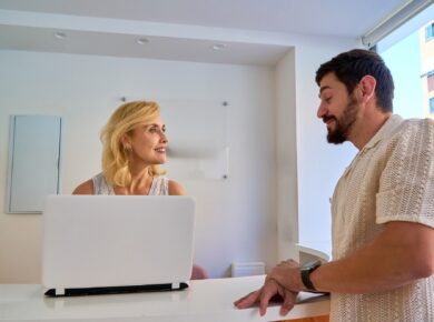 Woman and man having a conversation at a reception desk with a laptop